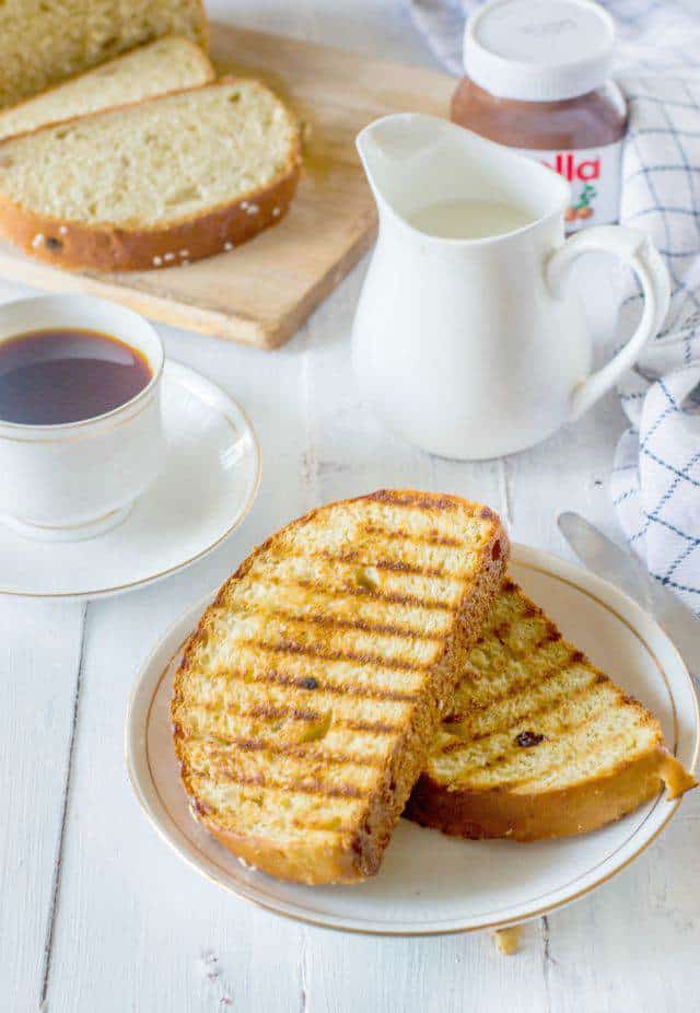 Toasted slices of artos greek celebration bread on a white plate along with a cup of tea