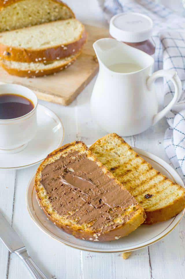 Nutella spread on a slice of artos greek celebration bread serve along with a cup of tea and a jug of milk