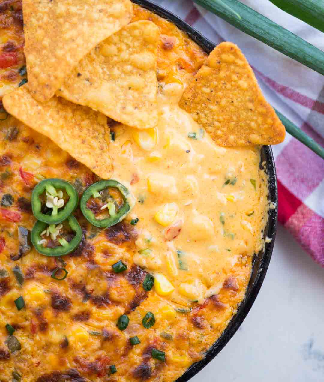 Corn dip made with mexican flavours has golden crust on top and nachos dipped into the cheesy creamy dip under the crust.