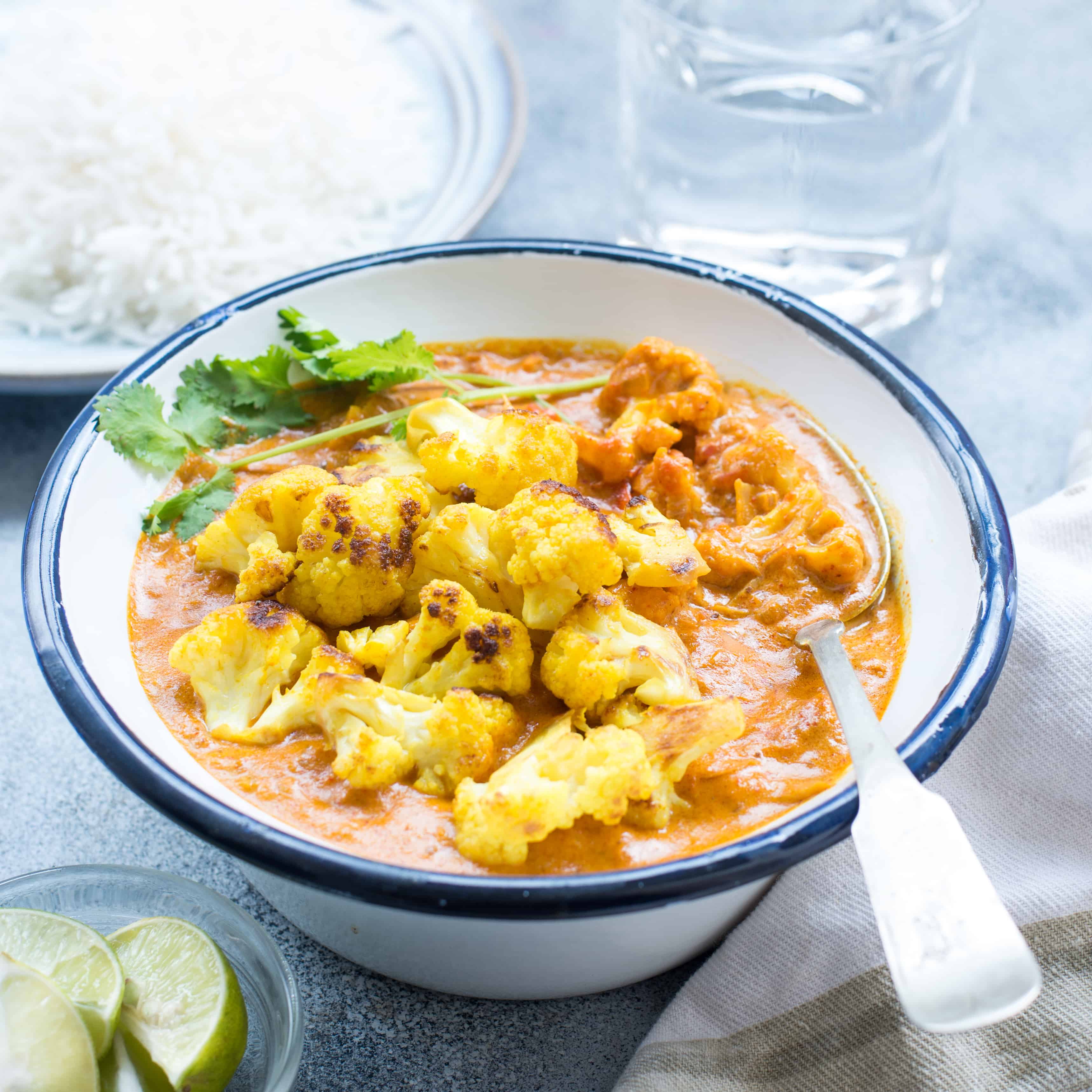 Indian curry with cauliflower florets in a white bowl.