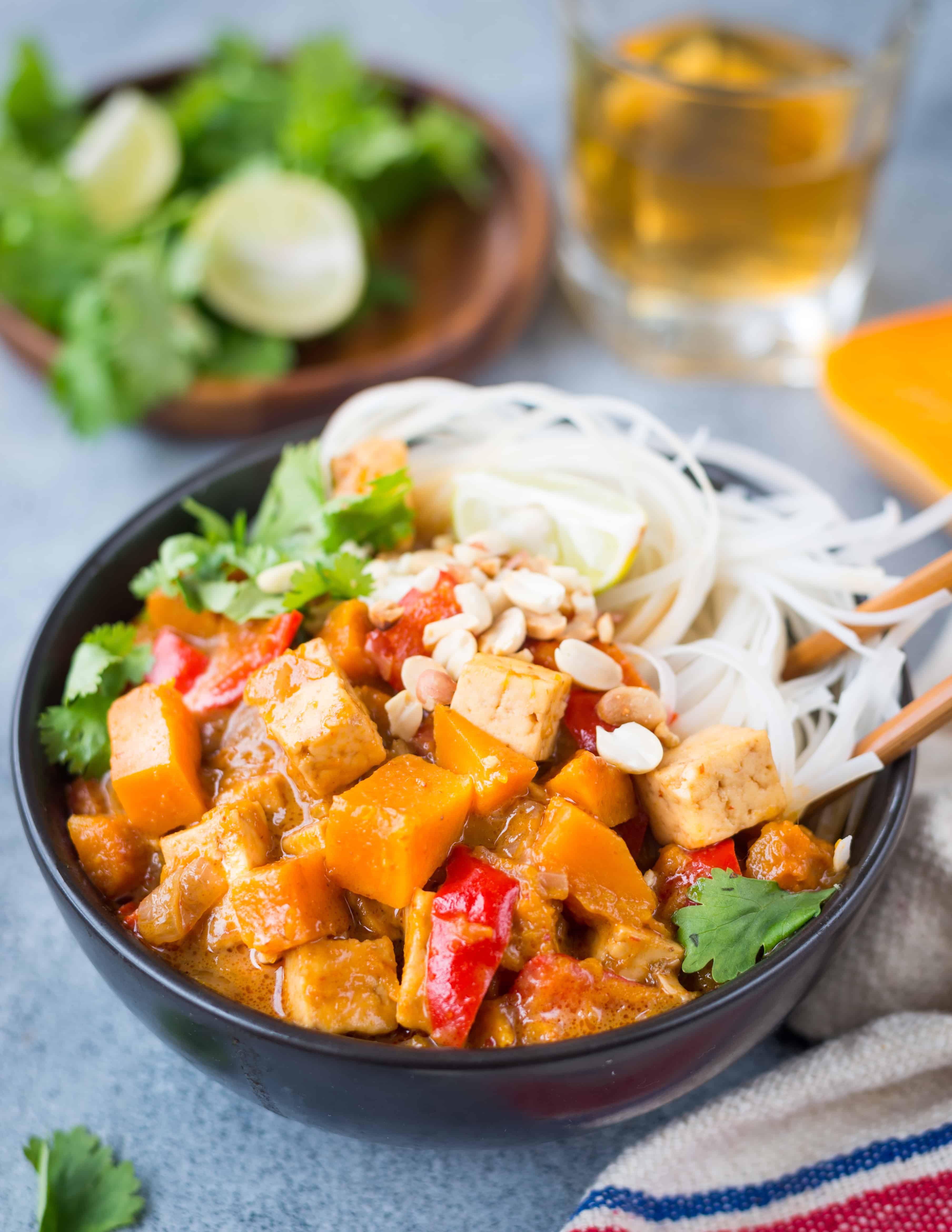 Side view of butternut squash curry served in a bowl with noodles.