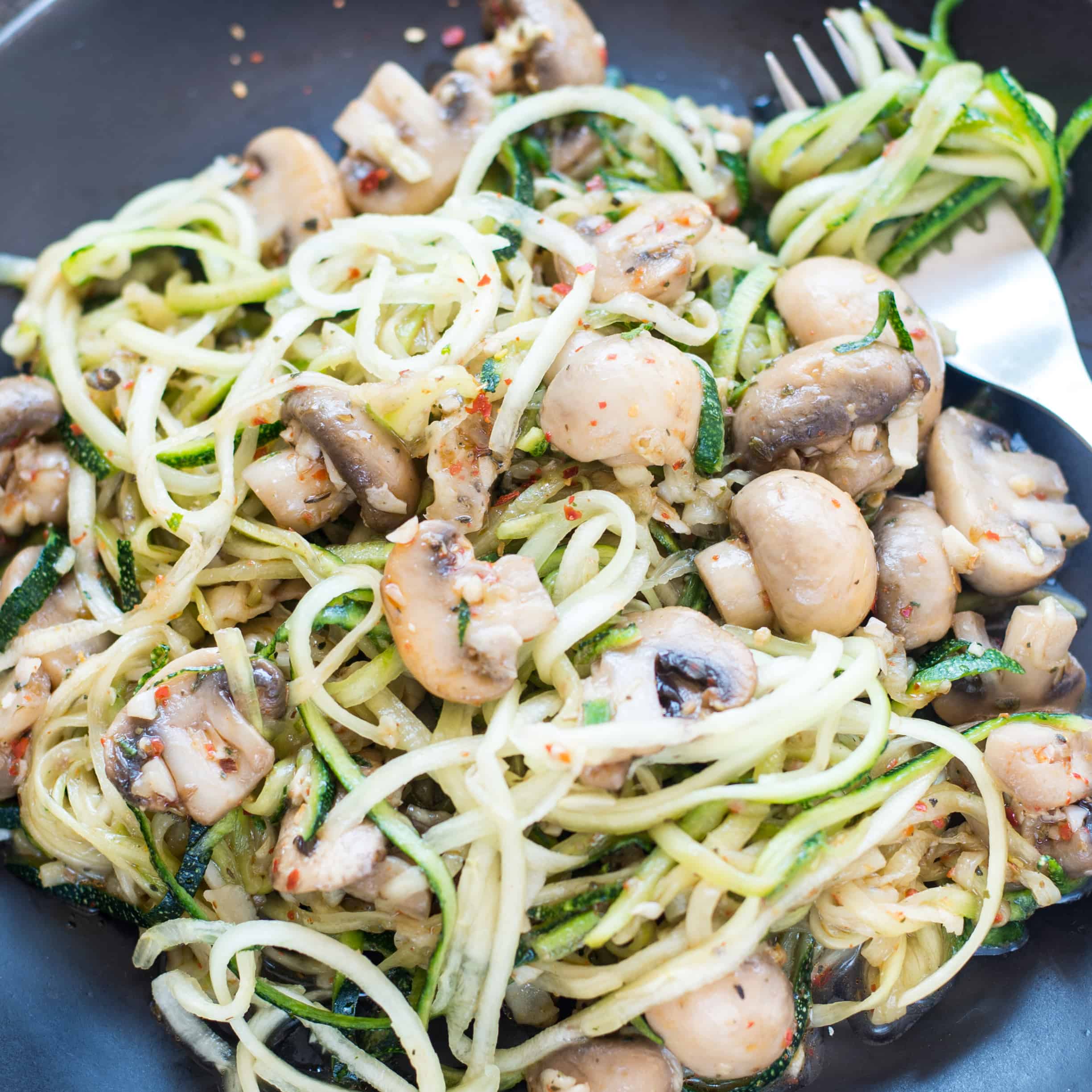 Close up image of zoodles tossed with garlic parmesan mushroom.