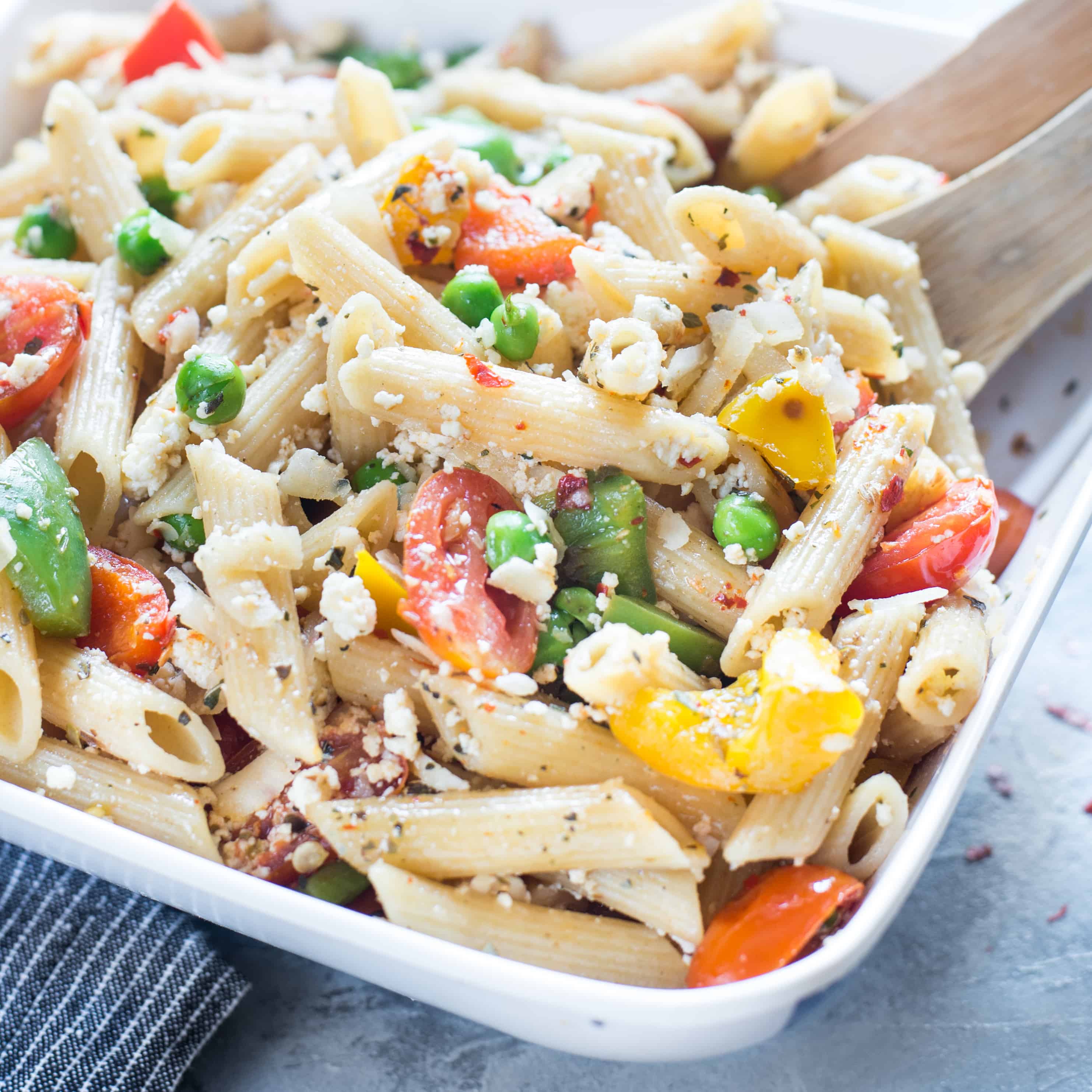 Side view of ricotta pasta salad served in serving dish, looking colorful and vibrant.