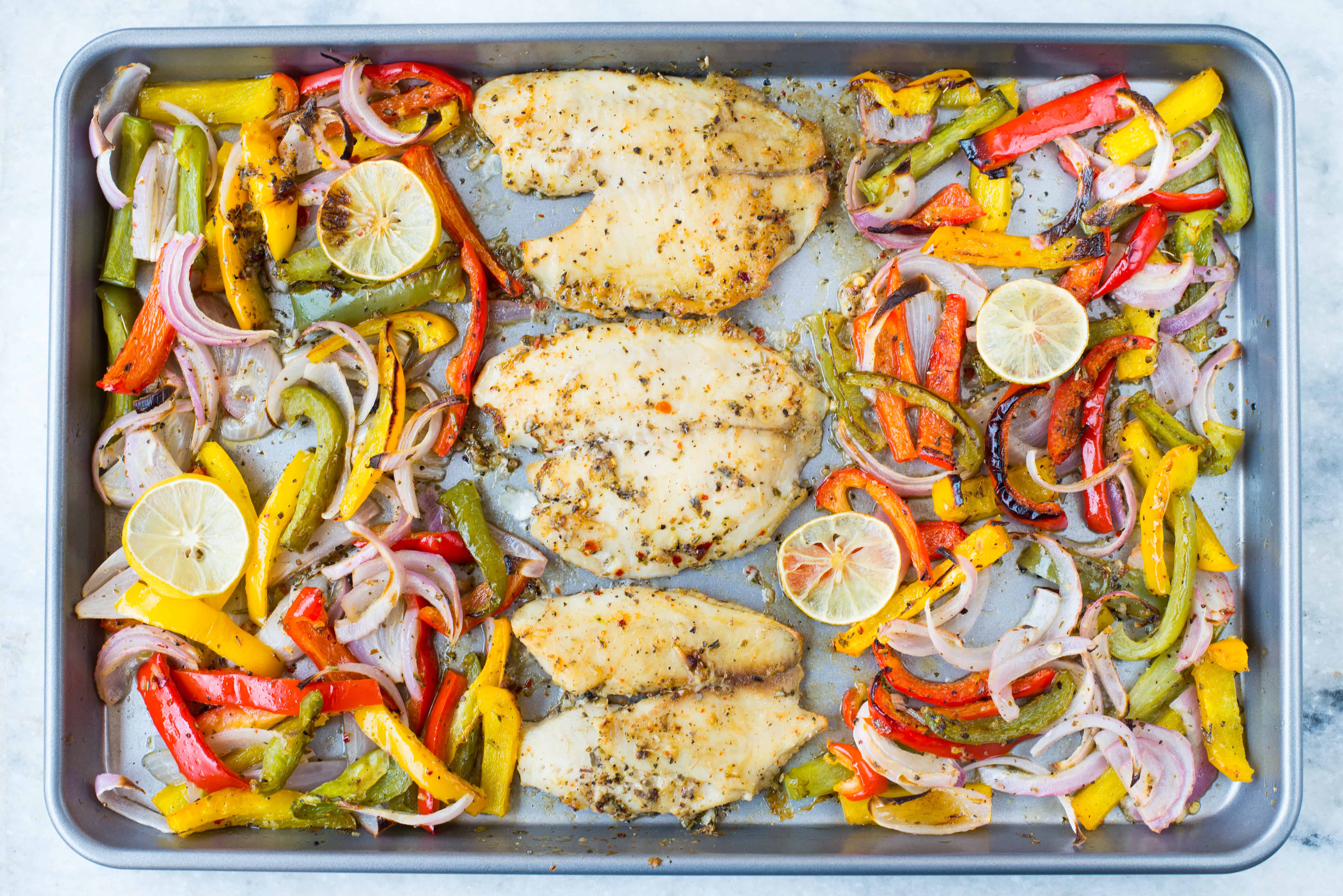 Oven baked Tilapia, onion and pepper in a delicious lemon garlic butter sauce. This Sheet Pan Lemon Garlic Baked Tilapia and Veggies is a healthy dinner made in under 20 minutes.