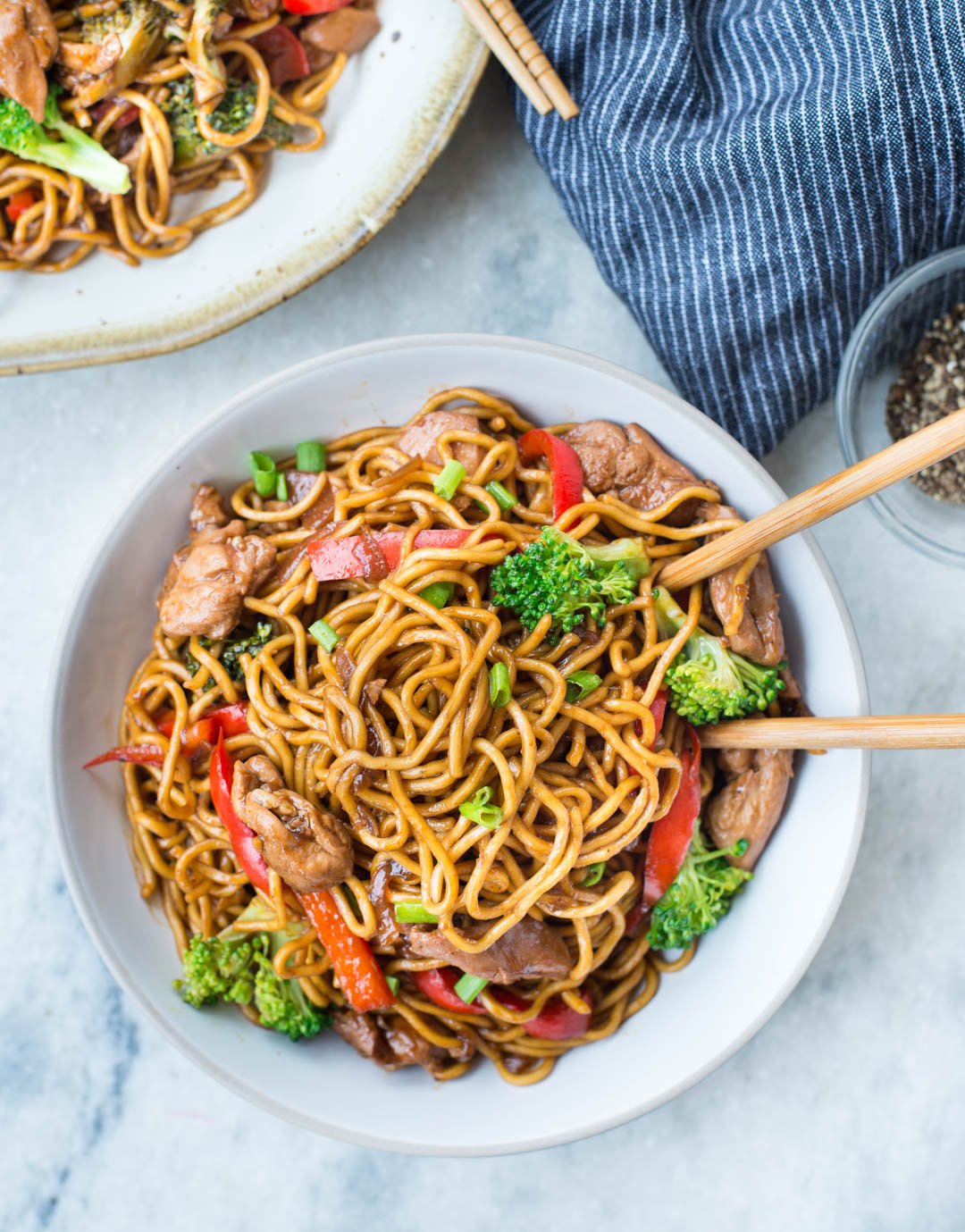 Photographie finale rapprochée de nouilles ramen au poulet sautées dans un bol avec des baguettes de côtelette.