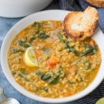 Bowl of red lentil soup served with bread slice