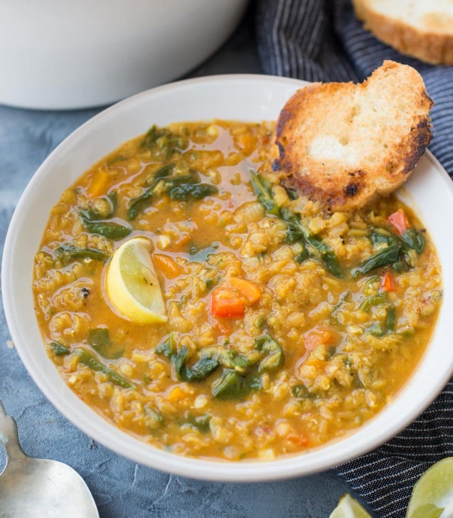 Bowl of red lentil soup served with bread slice