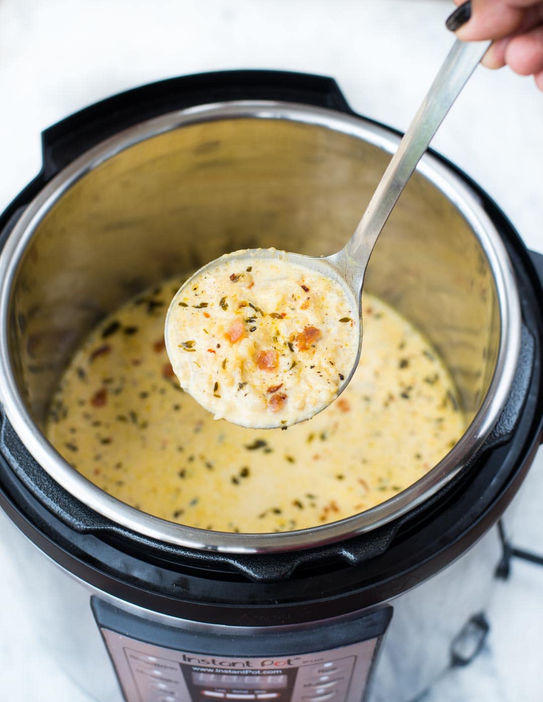 Ladle full of Low Carb Cauliflower Soup held atop the Instant Pot.