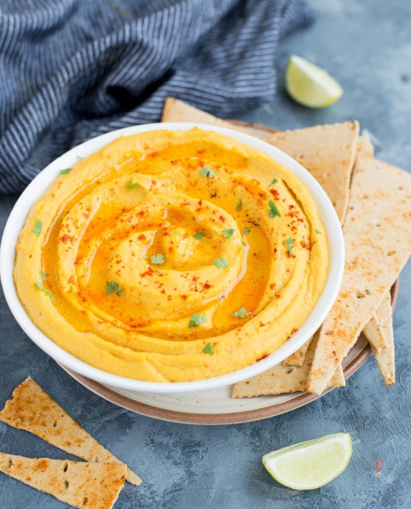 Side shot image shows hummus made with roasted sweet potatoes served with crackers