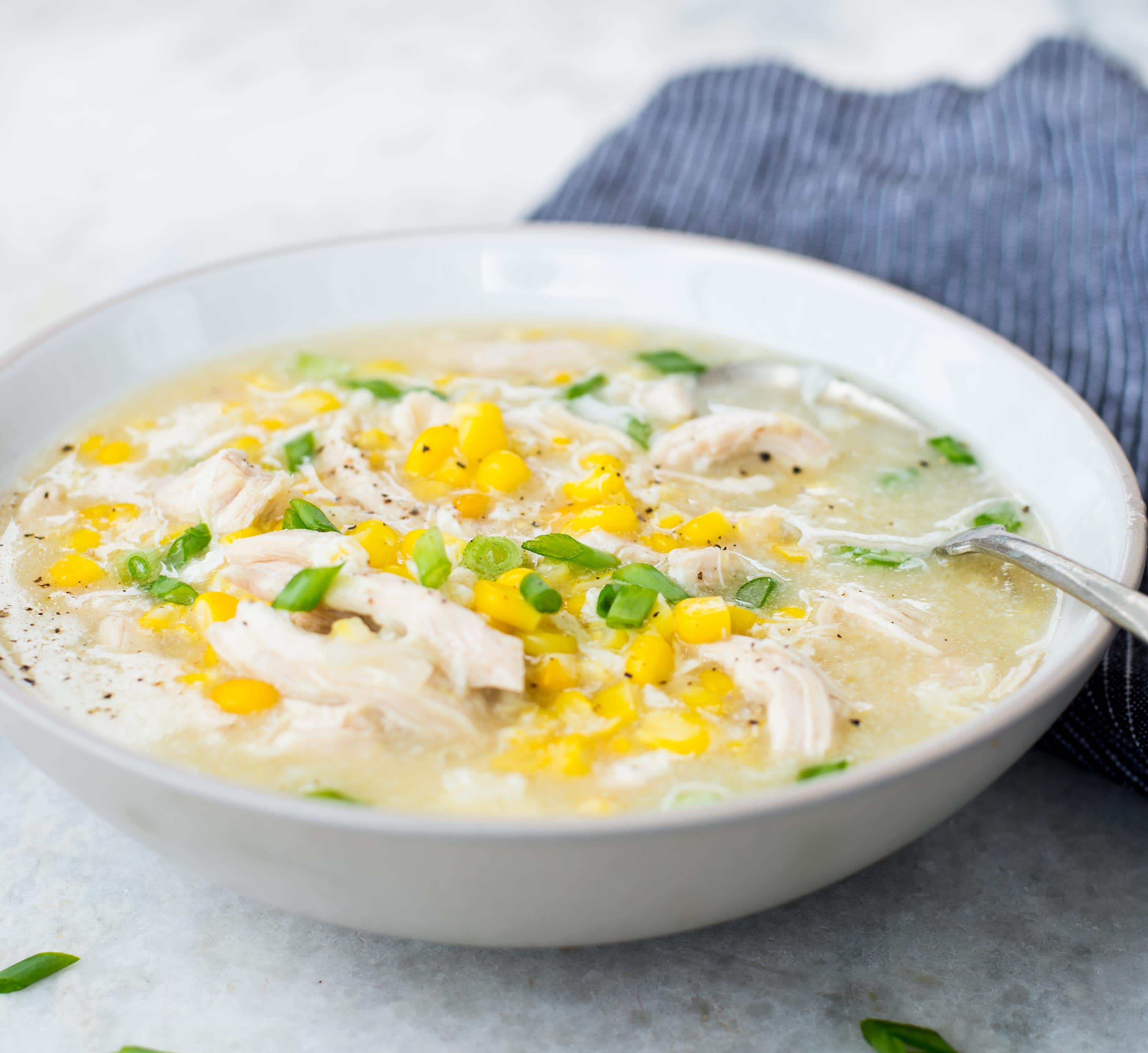 Side view of corn chicken soup which is thick and creamy and served in a white bowl.