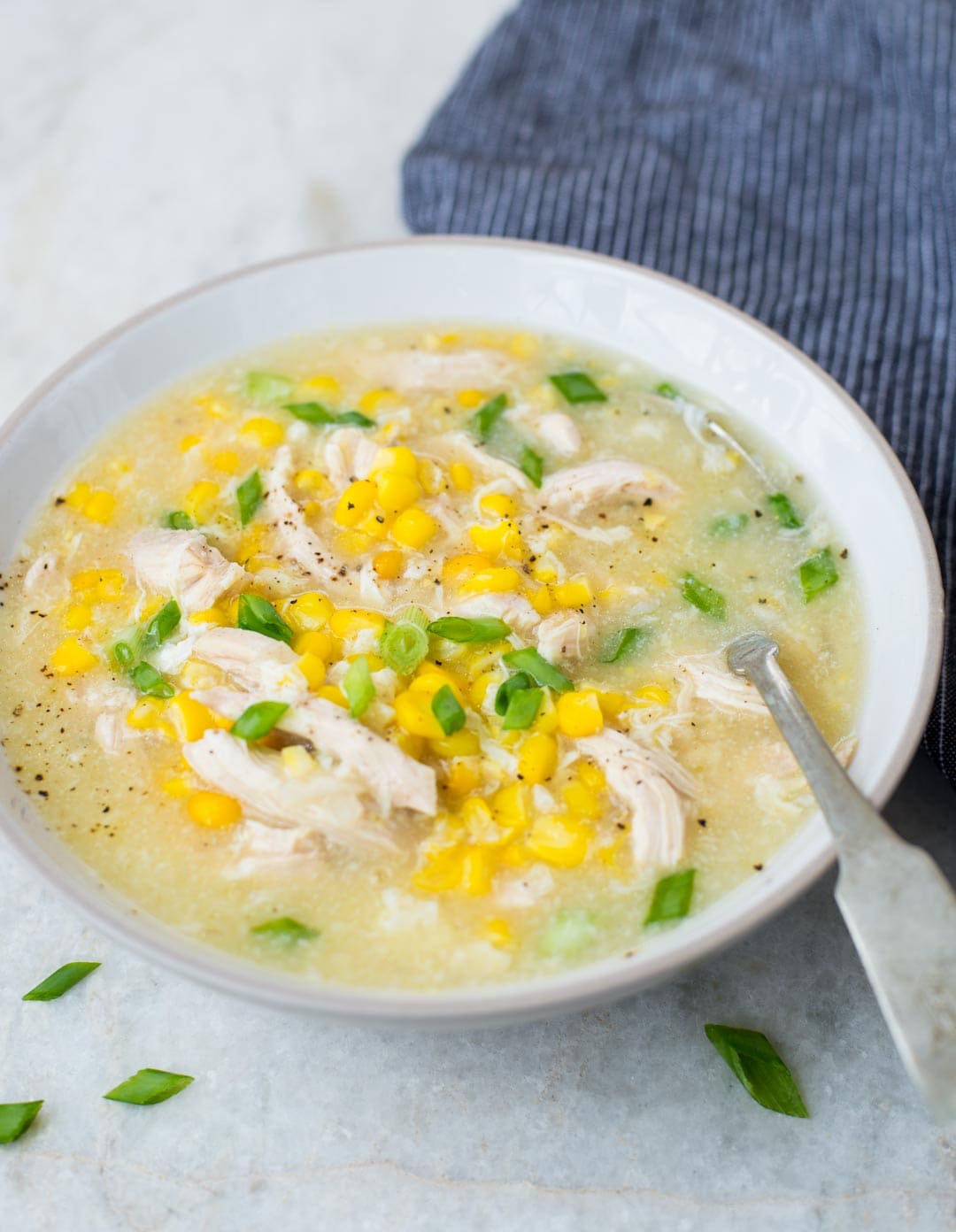 Corn chicken soup served in a white bowl is creamy, has rich flavors and soothing textures.