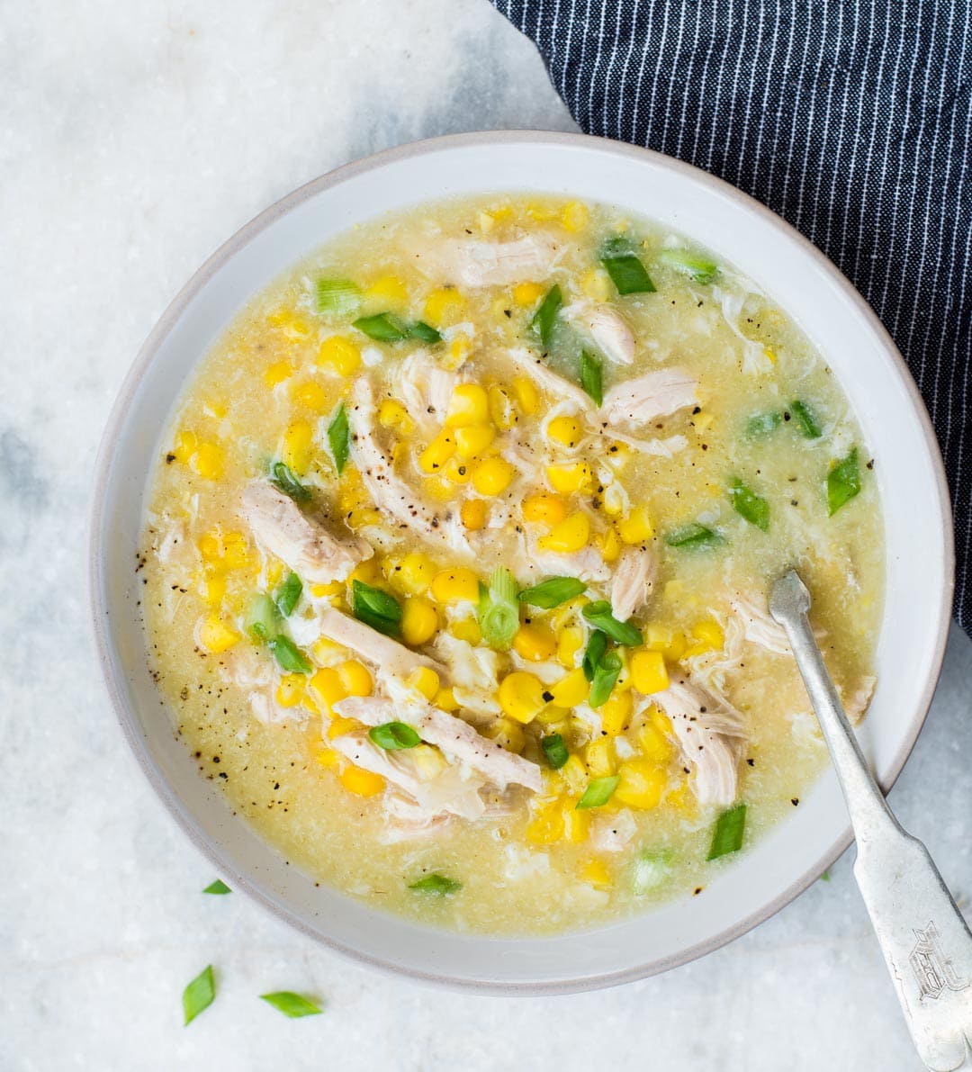 Top view of thick and creamy sweet corn and chicken soup served in a white bowl.