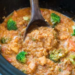 Close up shows quinoa and chicken in a slow cooker with broccoli florets.