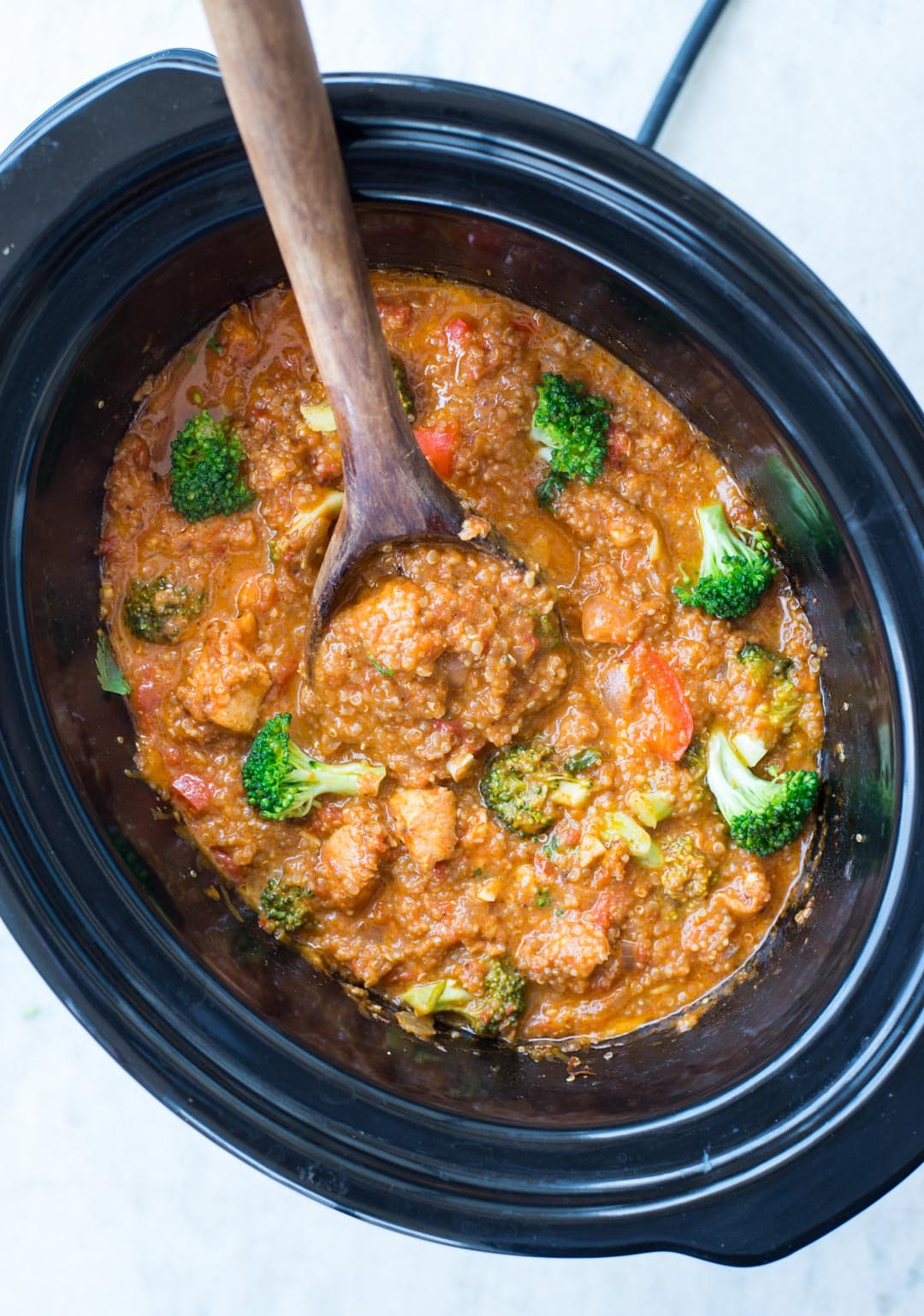 Top view of casserole dish, made of quinoa, chicken and broccoli, in a slow cooker.