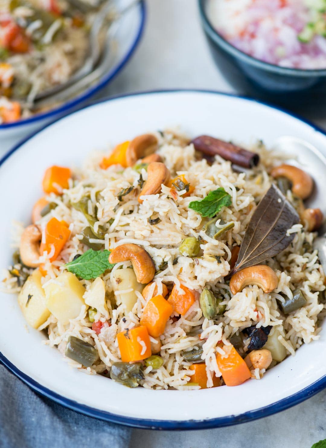 Close up shot of Vegetable pulao served in a white plate. Pulao is made with vegetables, whole spices and cashews.