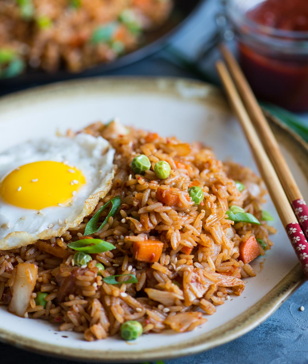 Close up look of Kimchi Fried rice served in a plate with sunny side up egg and chopsticks to eat with.