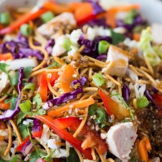 Close view of chinese chicken salad made with fried noodles, veggies and grilled chicken.