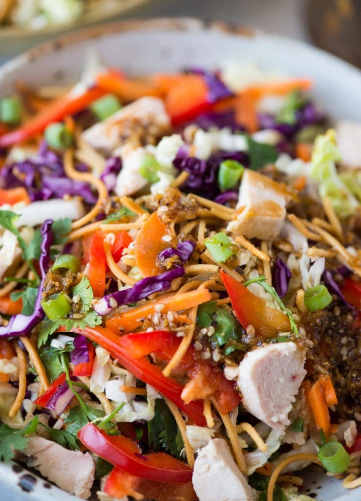 Close view of chinese chicken salad made with fried noodles, veggies and grilled chicken.