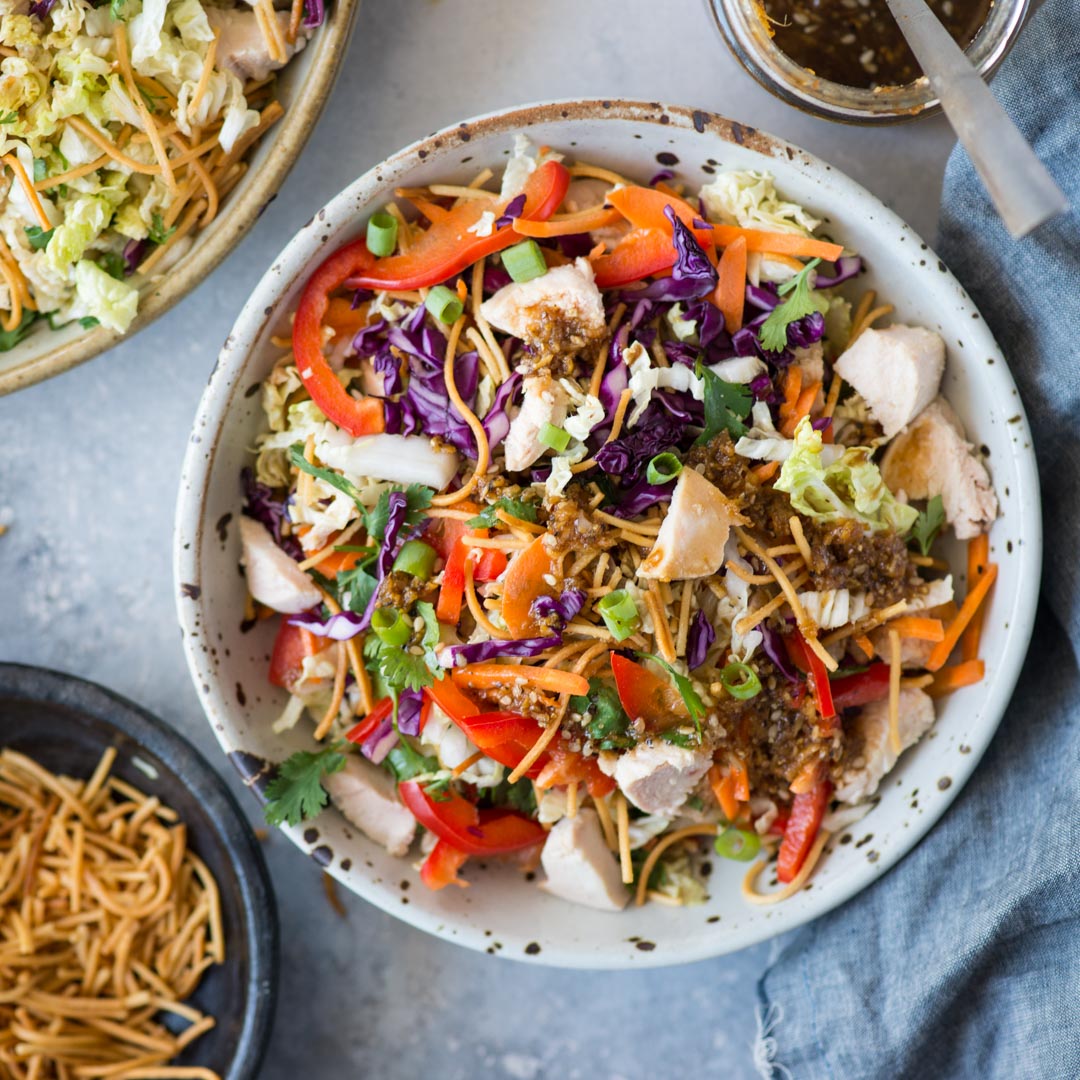 Top view of chinese chicken salad served in a white spotted bowl