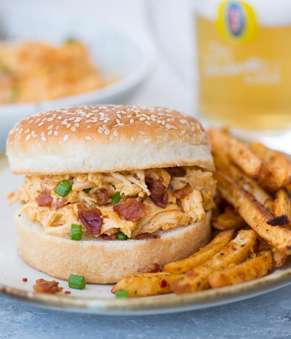 Crack chicken with bacon served in a bun alongside chips