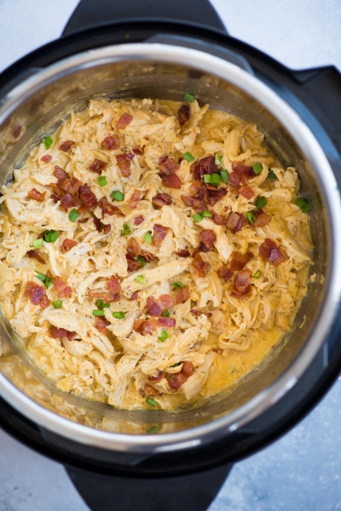 Close-up view of crack chicken made in Instant Pot topped with Instant Pot Crack chicken made with Chicken, Ranch Seasoning, cream cheese, Cheddar cheese and crispy bacon is incredibly delicious. This low carb, Keto chicken takes only 10 minutes to make.