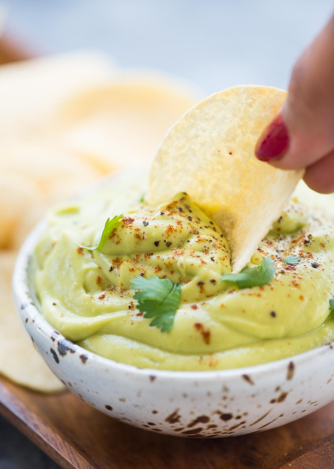 Potato chip dipped in a bowl of soft creamy tasty avocado dip