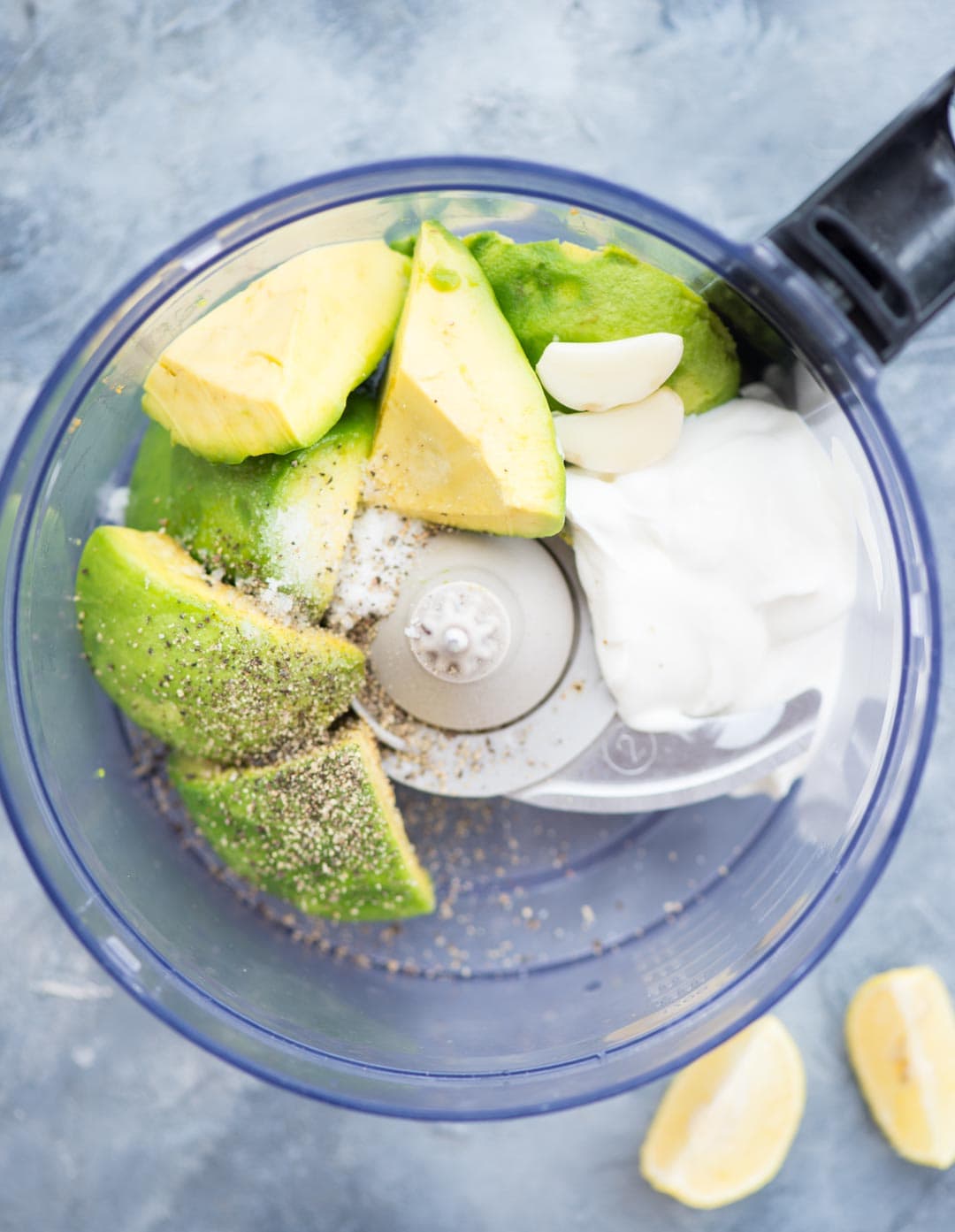 Image showing all ingredients needed to make creamy soft avocado dip added to a food processor - avocado, Sour cream, garlic, Lemon Juice