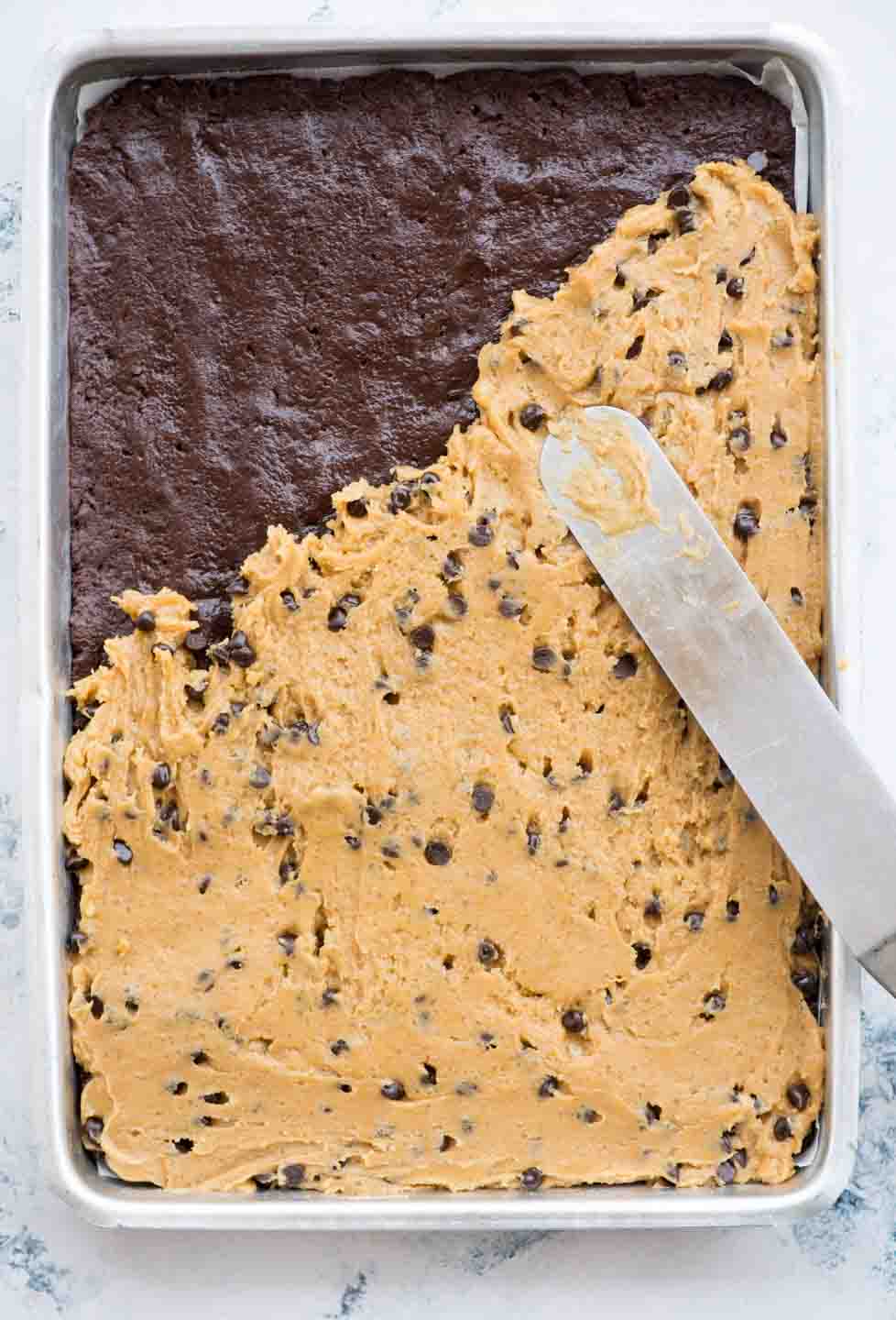 Double chocolate chip cookie bars with a fudgy chocolatey bottom are soft, chewy and made in a sheet pan. These Chocolate Chip Cookie Bars are made with single cookie dough (no separate dough for both the layers).