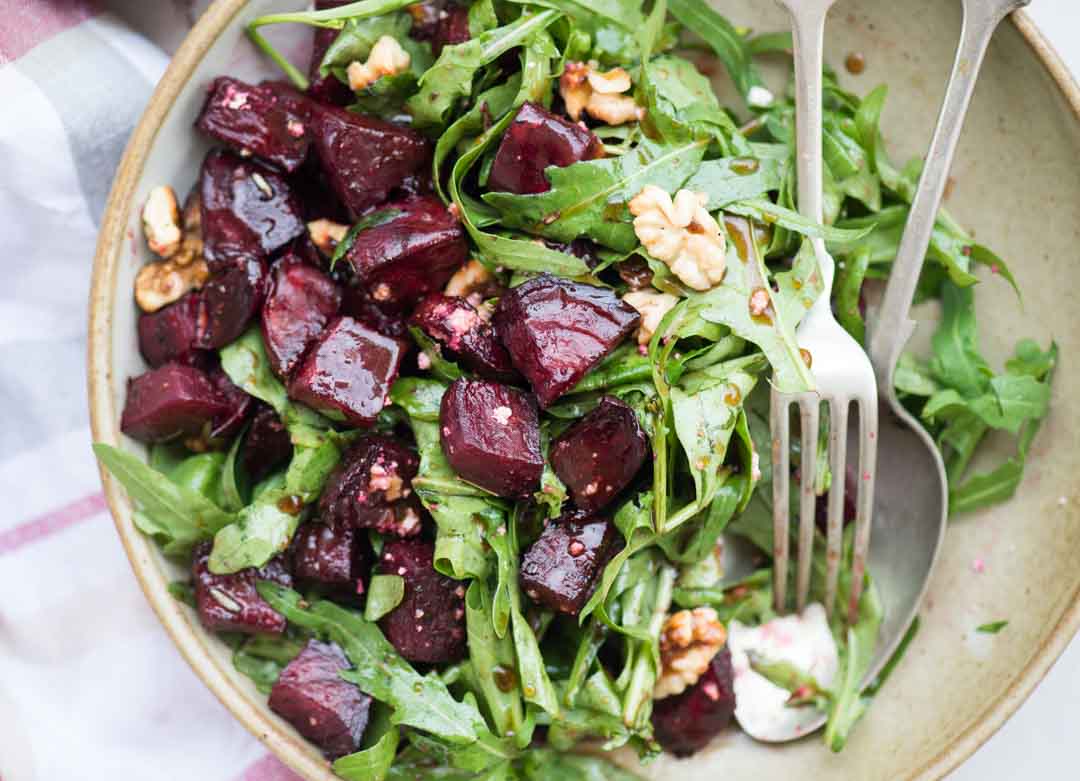 Arugula salad in a bowl with spoon and fork