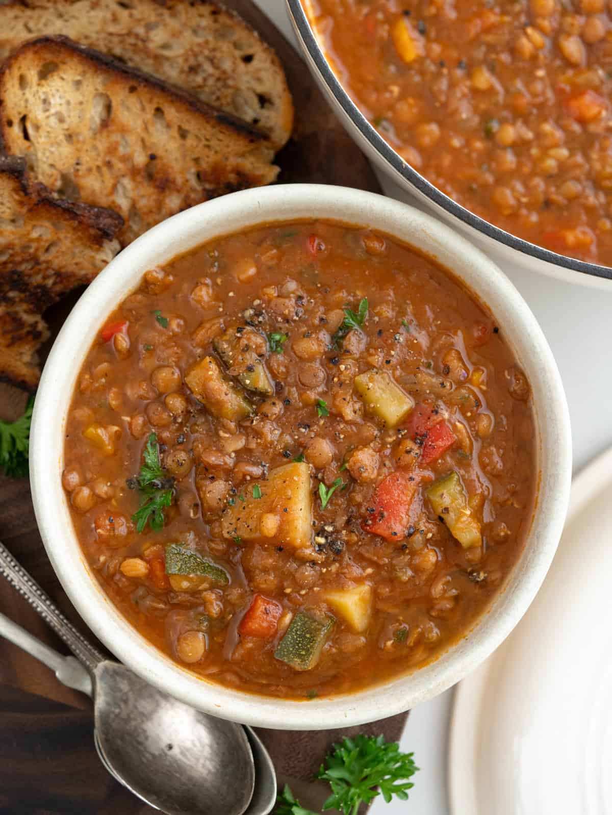 Bowl of vegetable lentil soup served with crusty sourdough bread. 