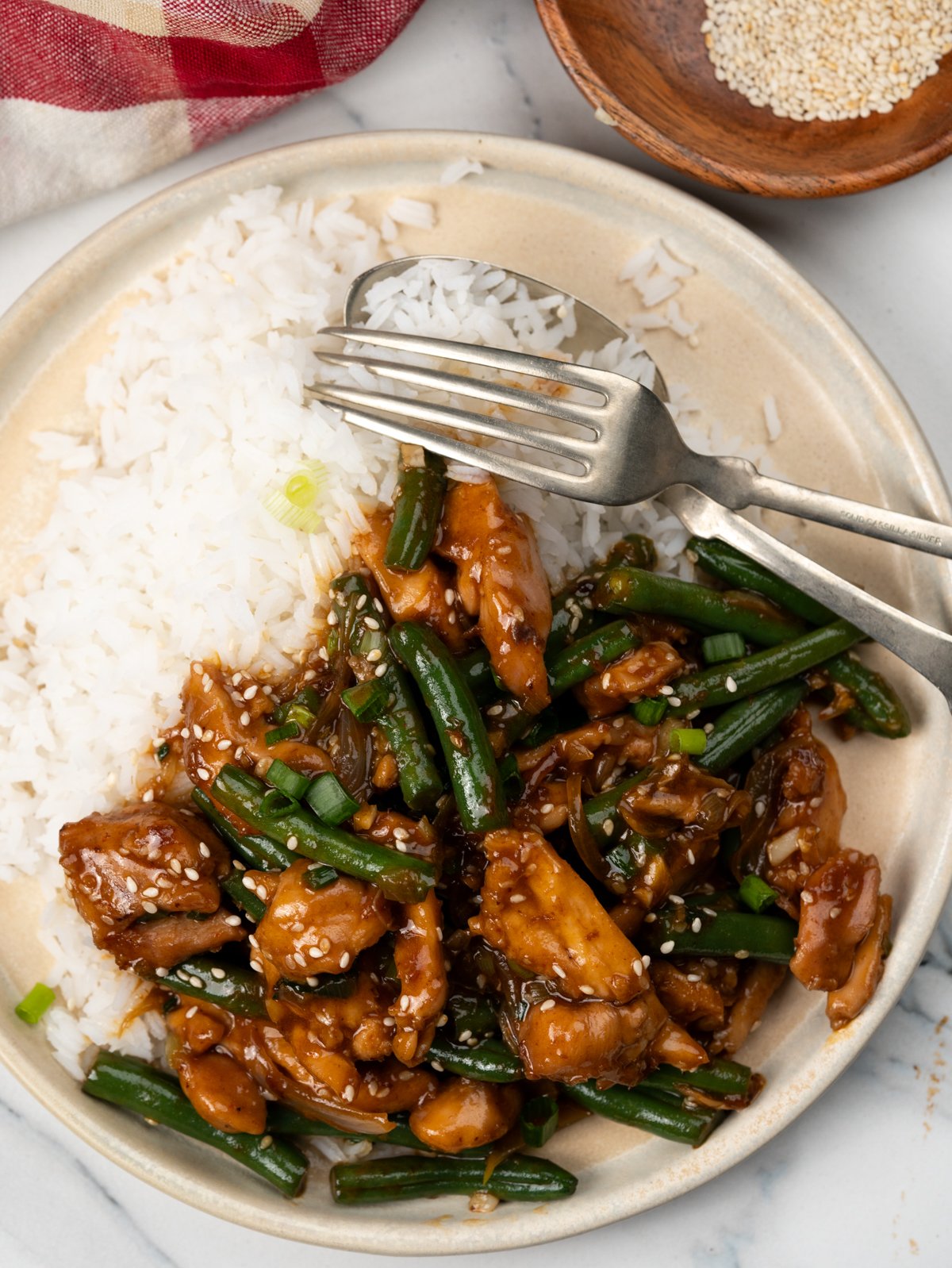 Chicken and green beans stir fried in a quick asian sauce is served with white rice.