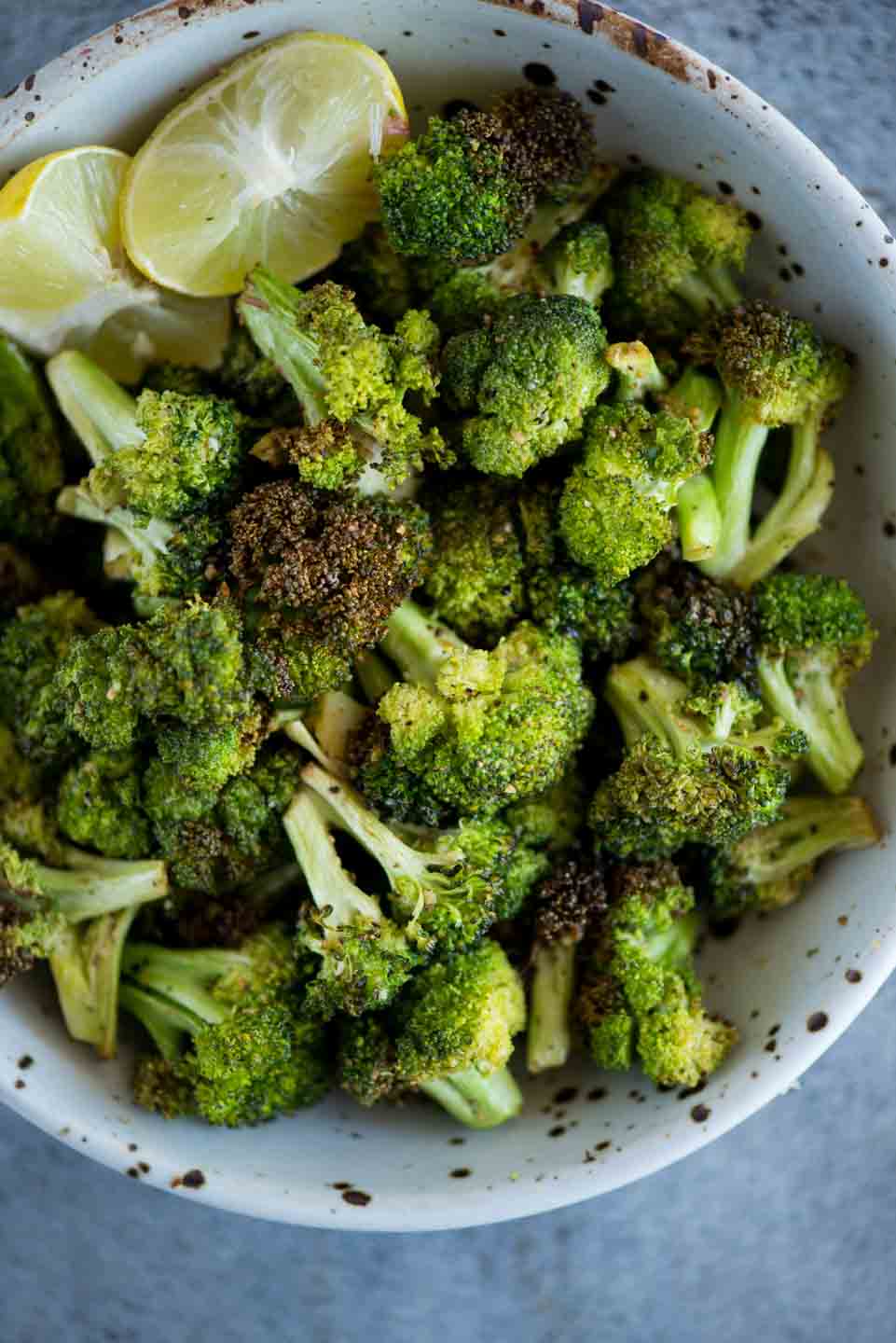 Bowl of Airfryer roasted broccoli with slices of lemon