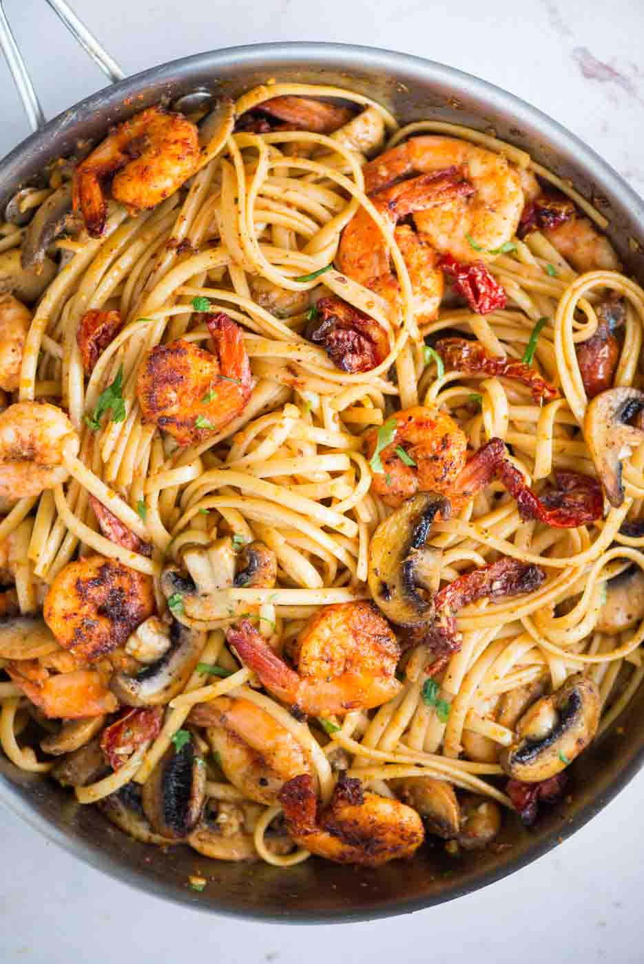 Mushroom Garlic Shrimp Pasta in a mildly spiced buttery sauce is light and loaded with flavour. Caramelized mushrooms, Juicy shrimps, Sundried tomatoes, all these goodness in one pan, makes it a  perfect meal on any occasion. 