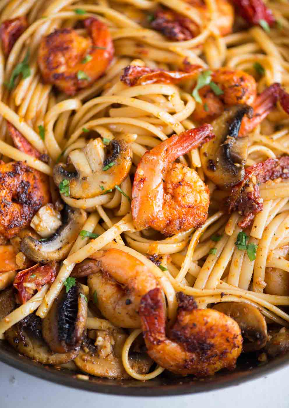 Mushroom Garlic Shrimp Pasta in a mildly spiced buttery sauce is light and loaded with flavour. Caramelized mushrooms, Juicy shrimps, Sundried tomatoes, all these goodness in one pan, makes it a  perfect meal on any occasion. 