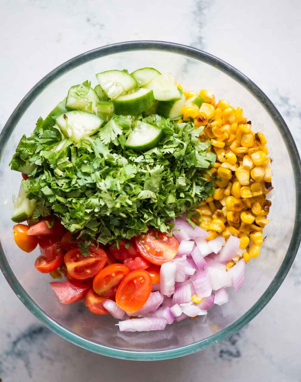 Chopped cucumber, roasted corn, onion, tomatoes and coriander leaves assembled to make corn salad