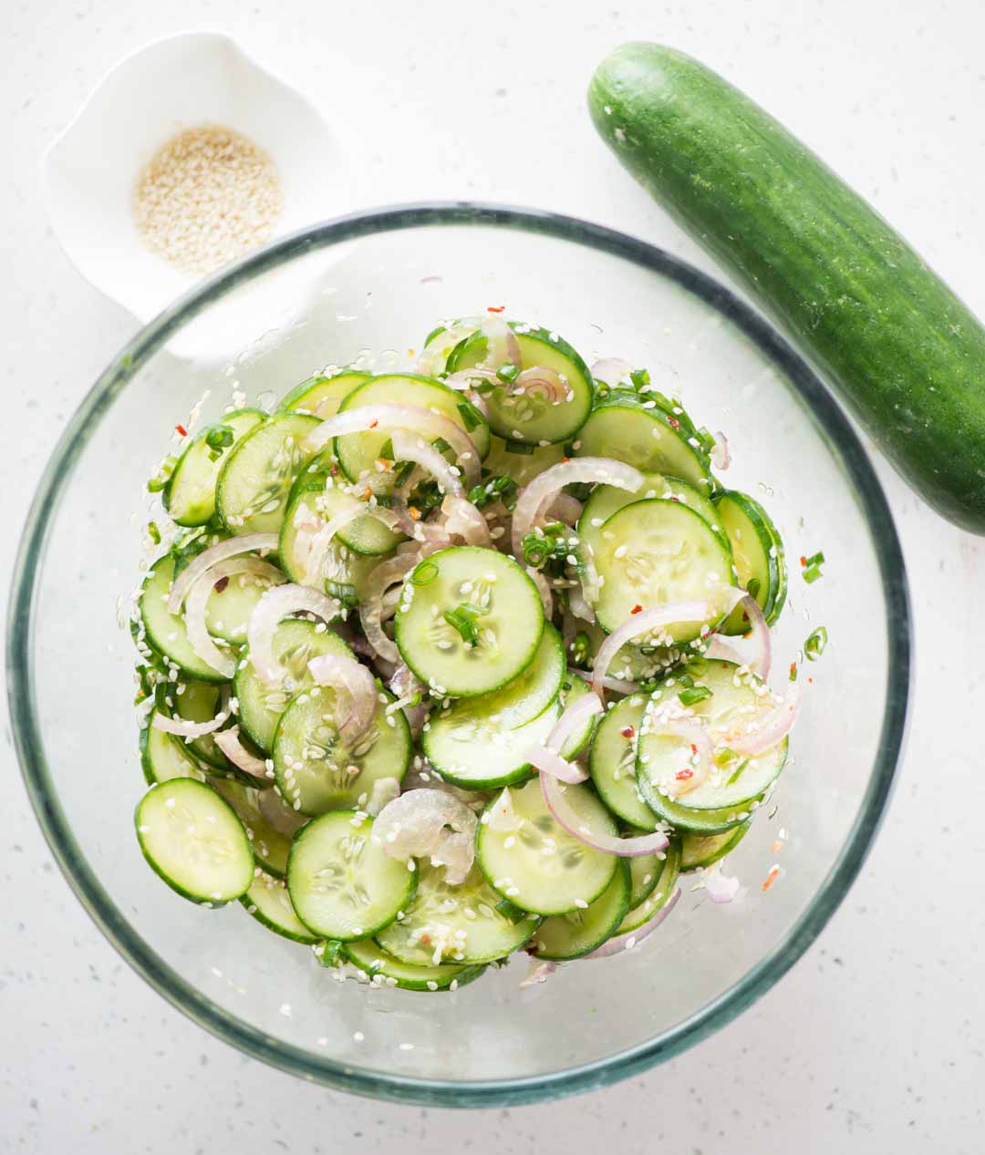 Ingredients for cucumber salad tossed in a large bowl.