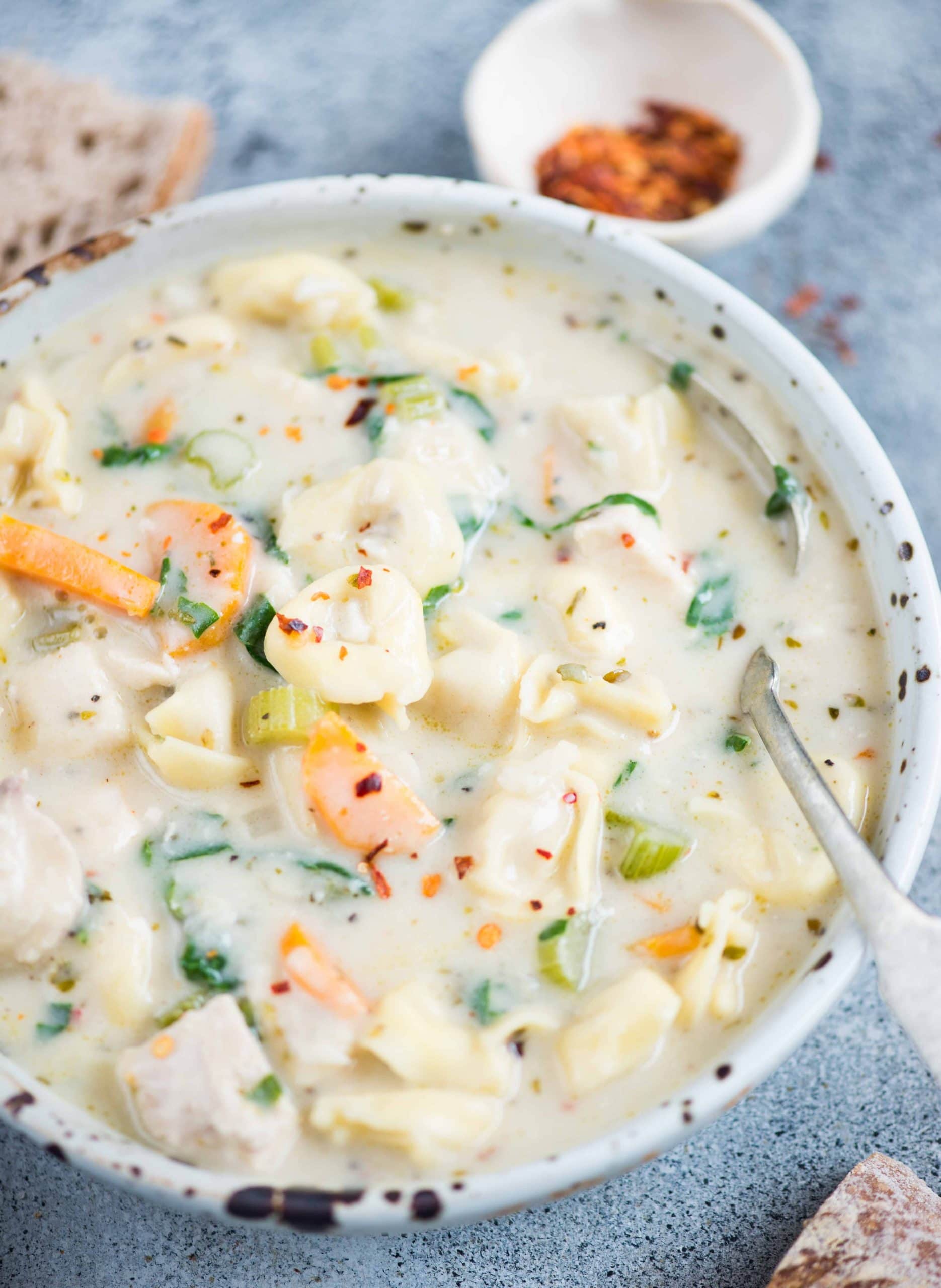 close up image of chicken tortellini soup served in a white bowl