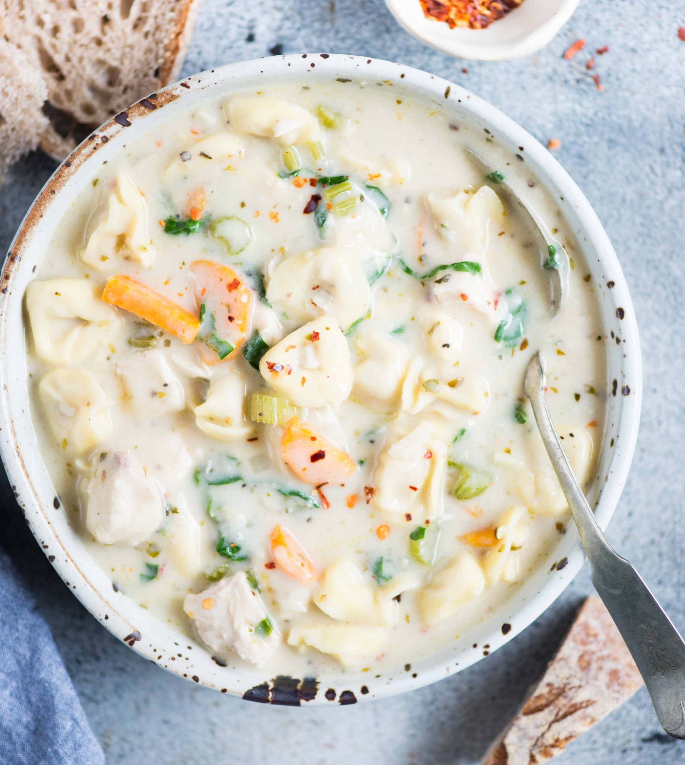 creamy Chicken Tortellini Soup served in a white bowl with spoon