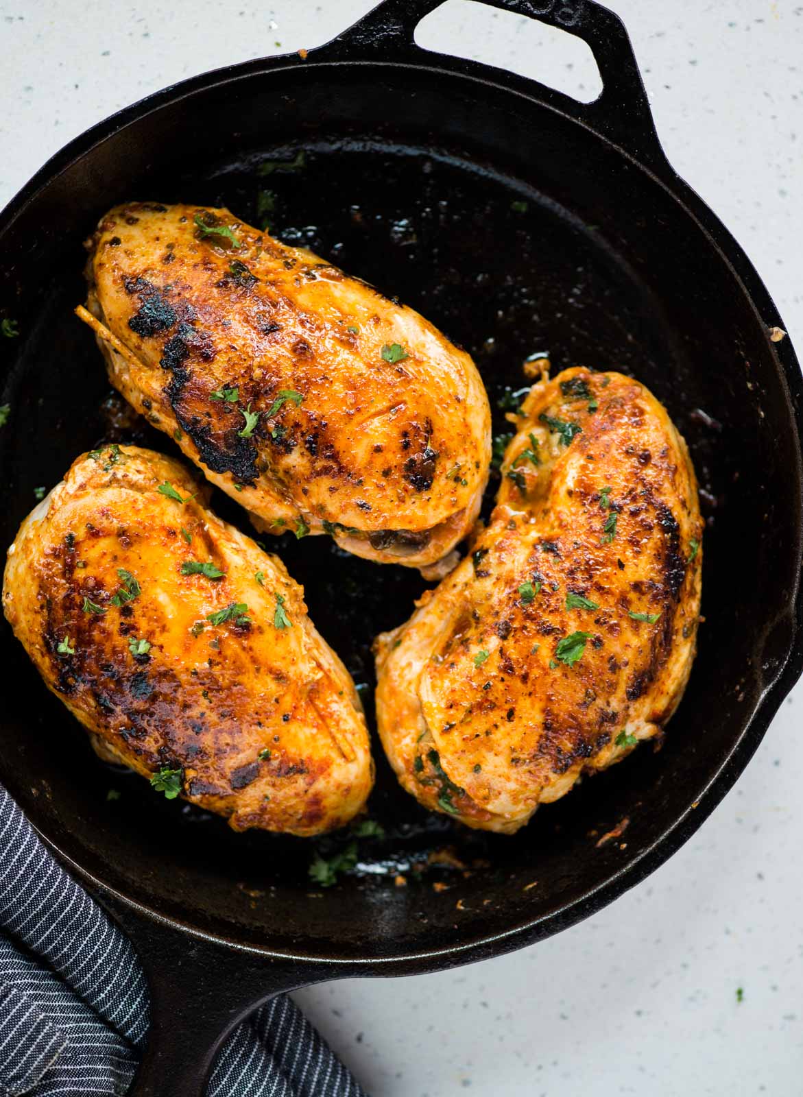 Three Chicken breasts with a stuffing of cheese, mushroom and spinach cooked on a cast iron pan.
