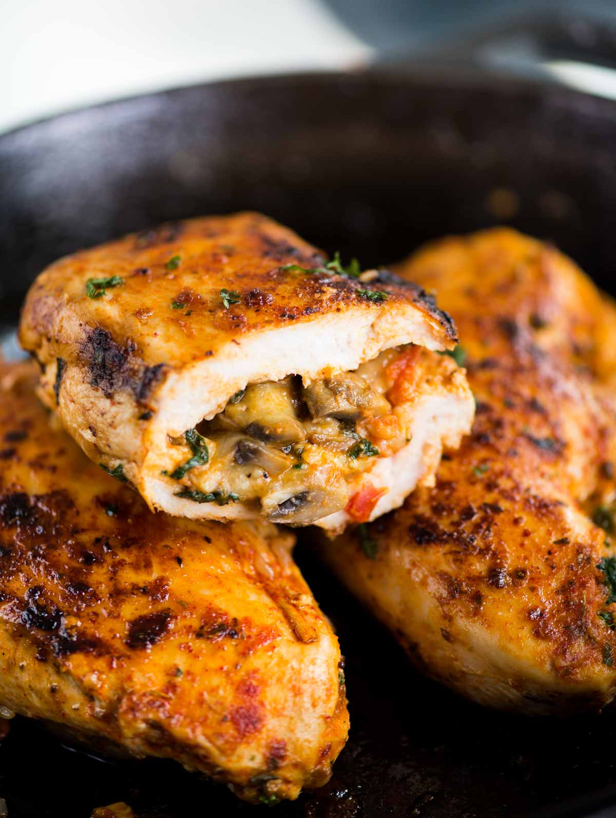 Close up view of a Stuffed Chicken breast cut in half. The Mushroom spinach and cheese stuffing is oozing out.