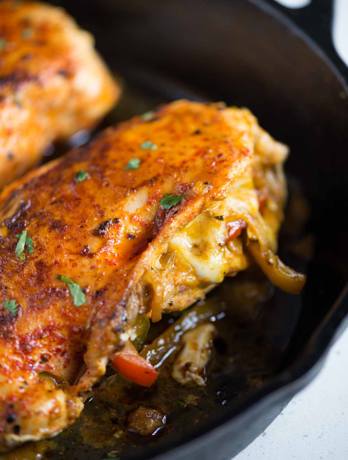 Featured image of baked chicken breasts with fajita-stuffing inside, served on a black plate.