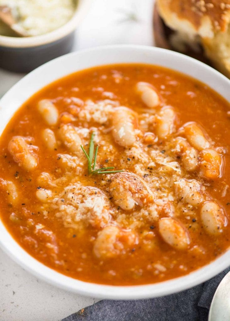 Closeup picture of tomato white bean soup served in a bowl with parmesan cheese on top