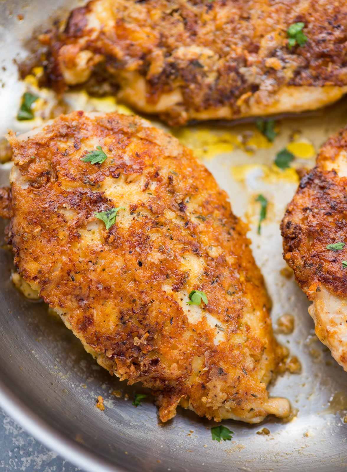 Close up of a parmesan crusted chicken breast piece. Shows a nice crispy and golden brown crust made of parmesan cheese.