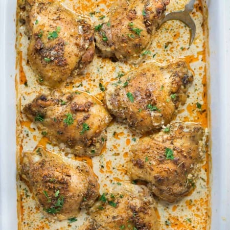 Crispy Baked Chicken thighs in a creamy parmesan sauce can be made in the oven from start to finish. Perfectly seasoned chicken thighs are juicy with crispy skin is easy enough for a weeknight family dinner.