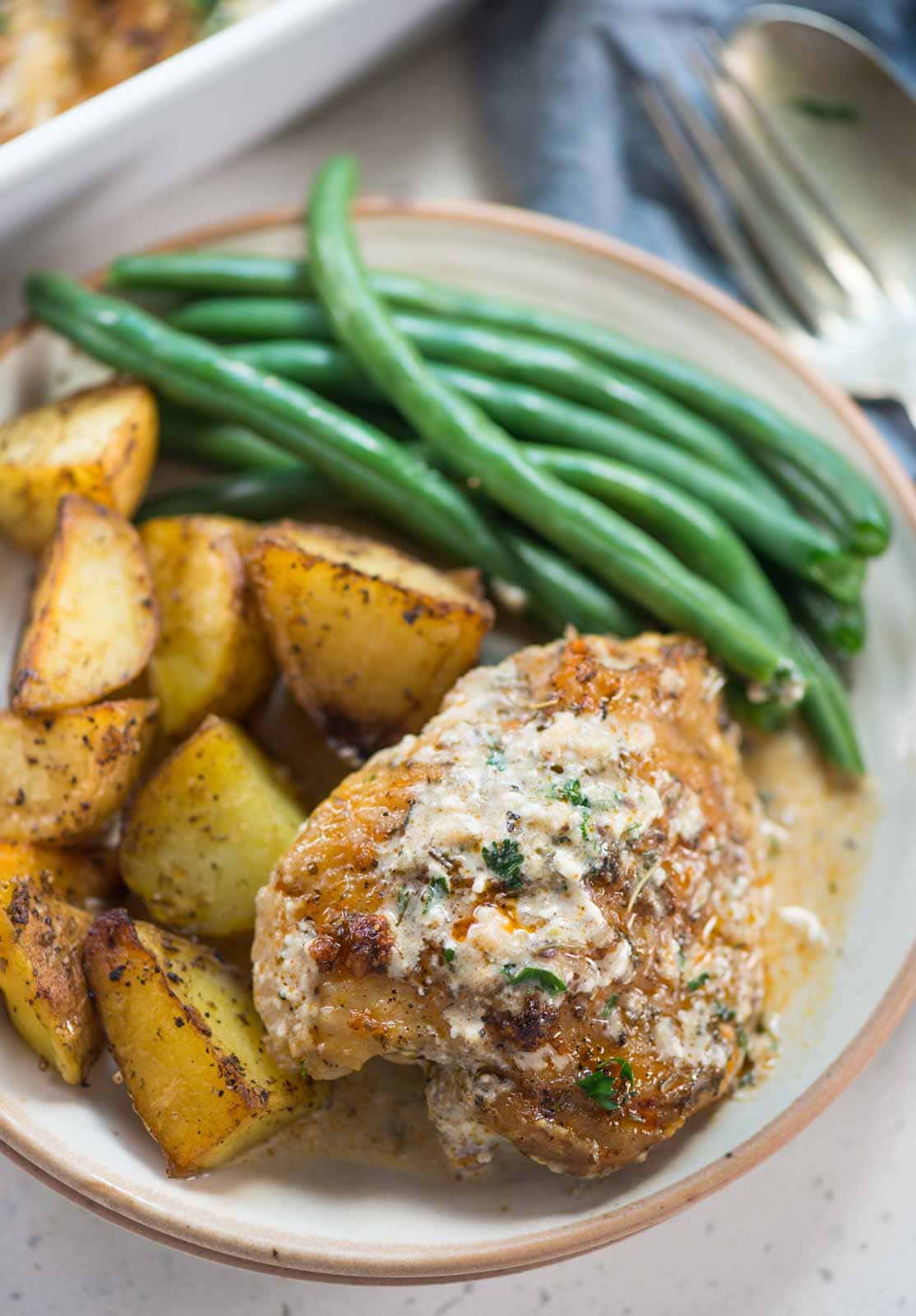 Crispy Baked Chicken thighs in a creamy parmesan sauce can be made in the oven from start to finish. Perfectly seasoned chicken thighs are juicy with crispy skin is easy enough for a weeknight family dinner.
