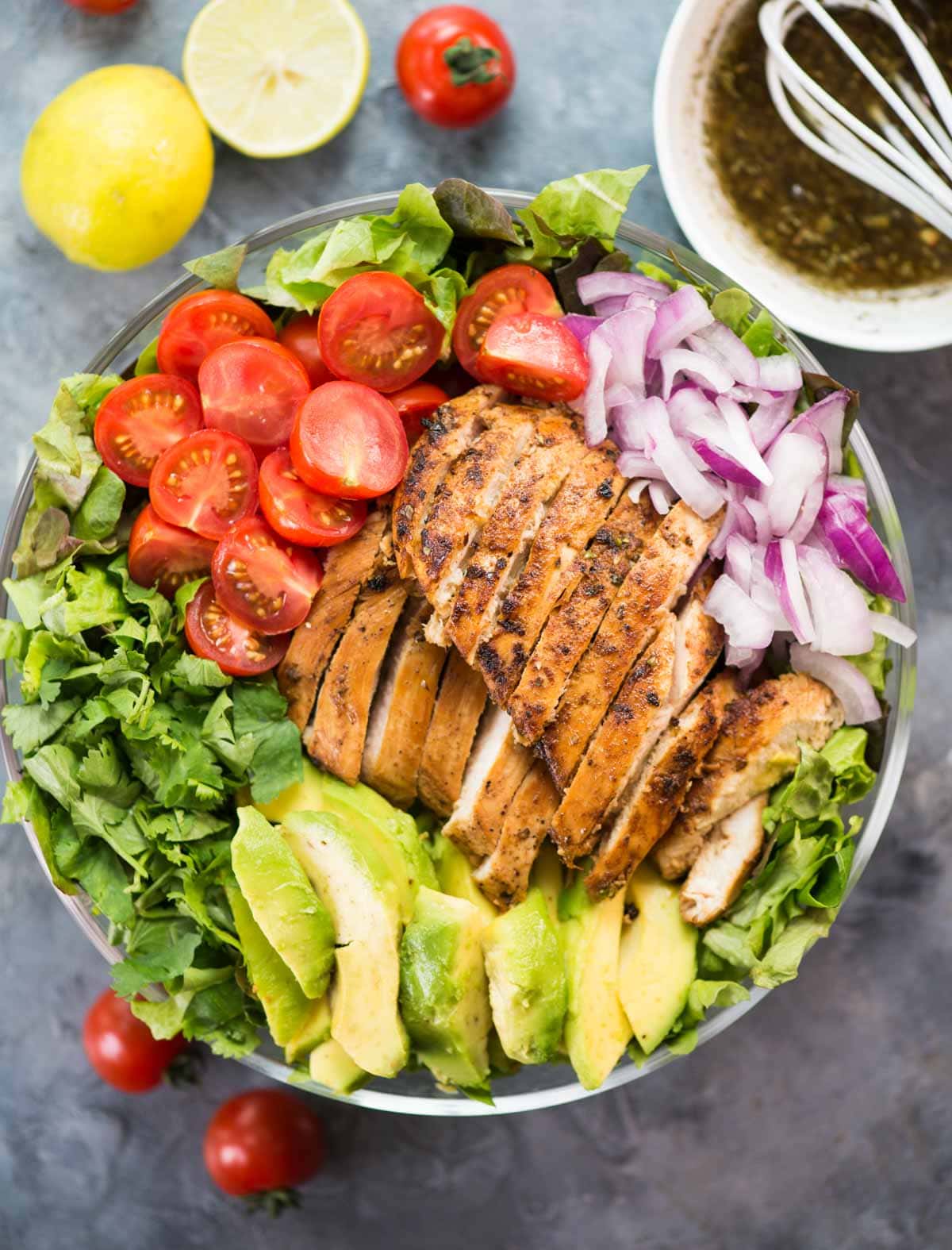 Shown in a bowl - Avocado Chicken Salad with a refreshing herb vinaigrette is loaded with fresh veggies, roasted chicken, and creamy Avocado.