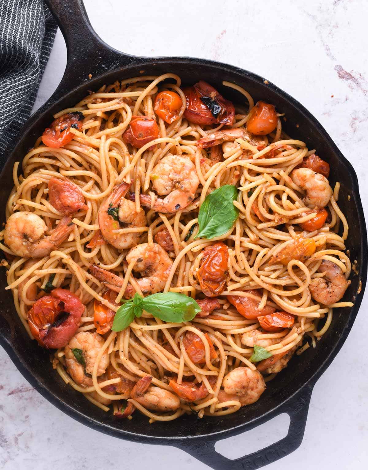Tomato pasta made with sauce from fresh cherry tomatoes and mixed with fried shrimps. Fresh basil garnished on top.