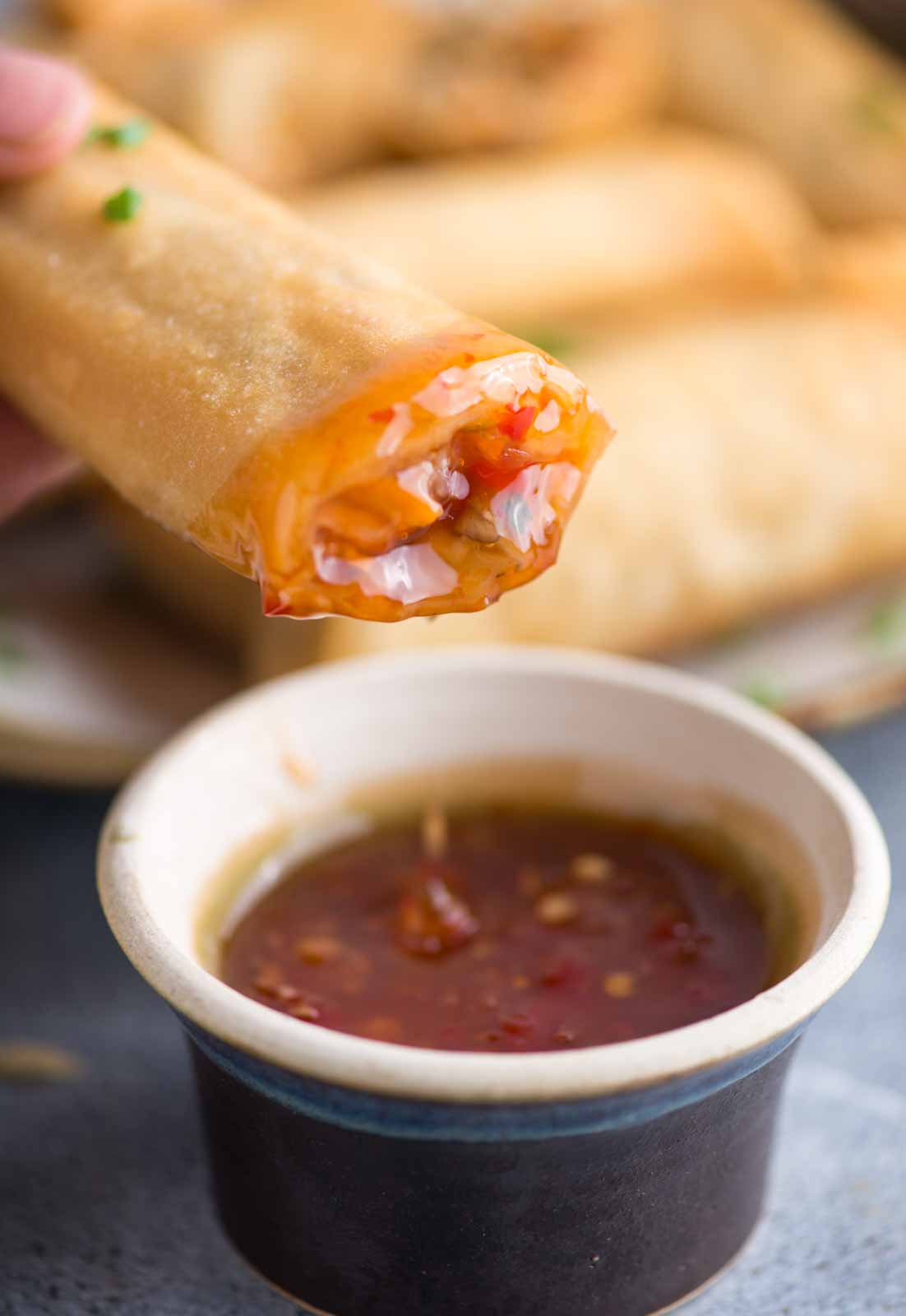 Shot of a crispy chicken spring roll after dipped in sauce and a bite taken.