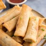 Final shot of crispy chicken spring rolls plated with a dipping sauce