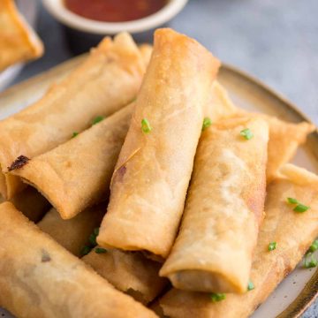 Final shot of crispy chicken spring rolls plated with a dipping sauce